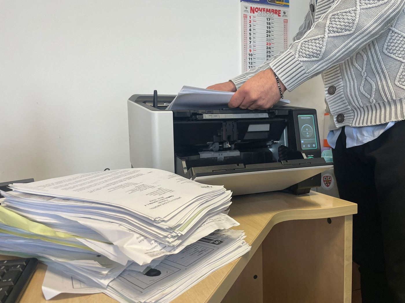 Un operatore inserisce una pila di documenti cartacei in uno scanner
